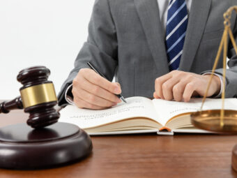 closeup-shot-person-writing-book-with-gavel-table (1)